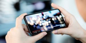 Zu sehen ist eine Person, die ein Smartphone in den Händen hält und Video-Inhalte anschaut.