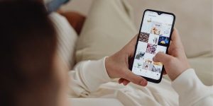 Zu sehen ist eine Person am Smartphone, die Inhalte auf Social Media anschaut.